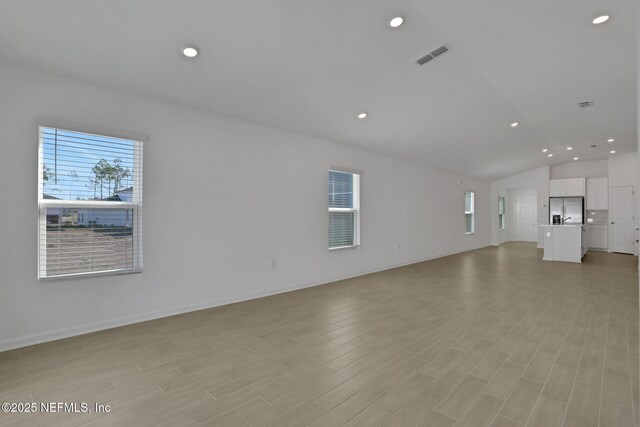 unfurnished living room with vaulted ceiling and light hardwood / wood-style floors