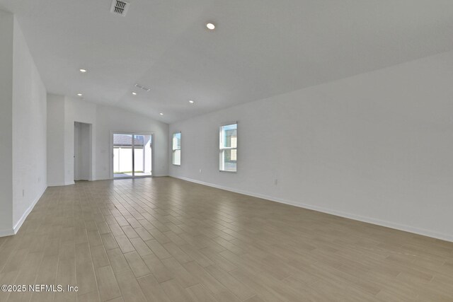 spare room featuring lofted ceiling and light hardwood / wood-style floors