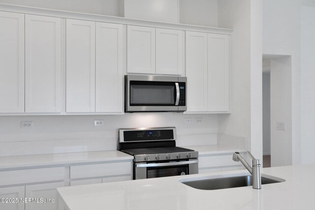 kitchen featuring stainless steel appliances, white cabinetry, and sink