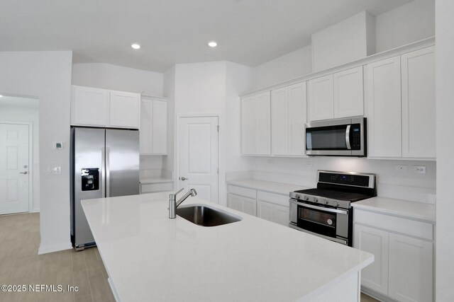 kitchen with white cabinetry, stainless steel appliances, and a center island with sink