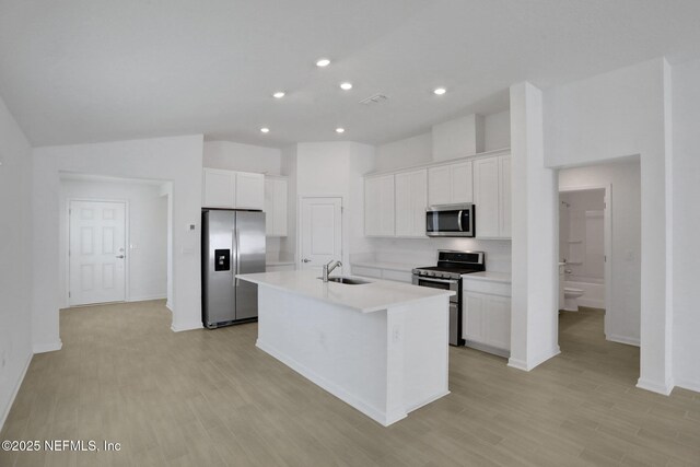 kitchen with appliances with stainless steel finishes, sink, an island with sink, and white cabinets