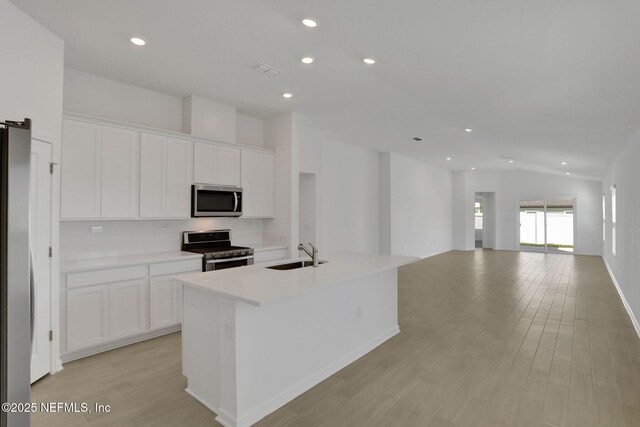 kitchen featuring stainless steel appliances, sink, white cabinets, and a kitchen island with sink