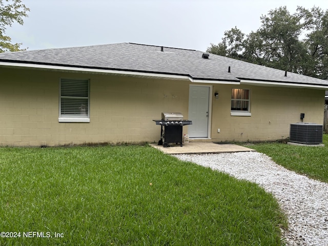 1555 Ibis Dr, Orange Park, FL 32065 - back of house featuring a shingled roof, concrete block siding, central air condition unit, and a yard