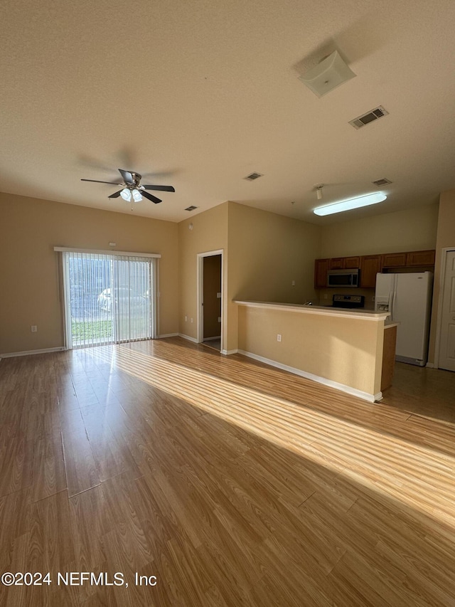 unfurnished living room featuring ceiling fan, light hardwood / wood-style floors, and a textured ceiling