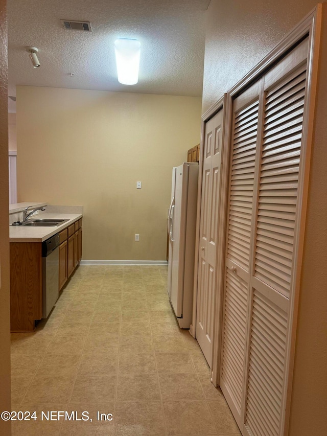 kitchen with sink, a textured ceiling, dishwasher, and white refrigerator