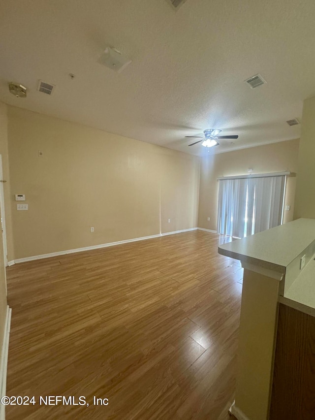 spare room featuring ceiling fan, light hardwood / wood-style floors, and a textured ceiling