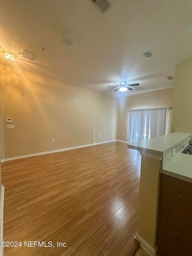 unfurnished room with ceiling fan, a textured ceiling, and light hardwood / wood-style floors