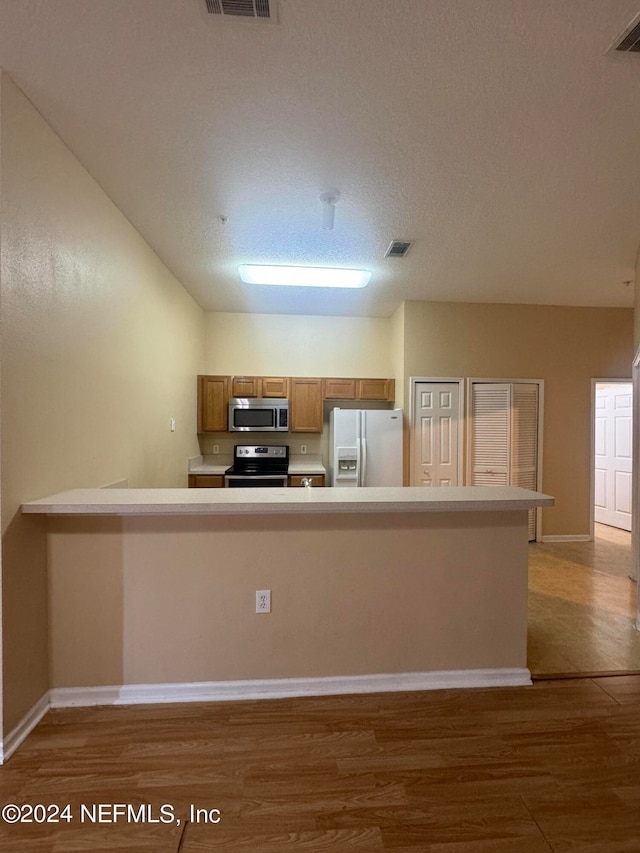 kitchen featuring appliances with stainless steel finishes, light hardwood / wood-style floors, and a textured ceiling