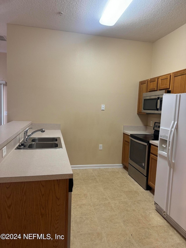 kitchen featuring stainless steel appliances, sink, and a textured ceiling