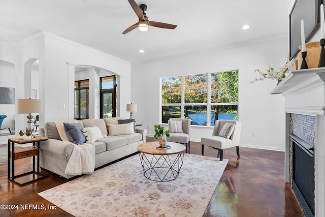 living room with a textured ceiling, ceiling fan, crown molding, and a tiled fireplace