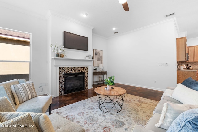 living room featuring crown molding, a fireplace, ceiling fan, and wood-type flooring