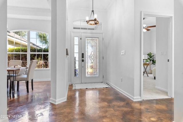 foyer entrance with ceiling fan with notable chandelier and ornamental molding