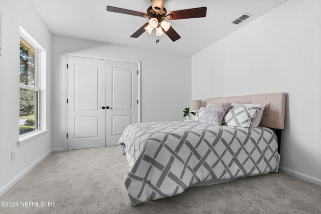 carpeted bedroom featuring a textured ceiling, a closet, and ceiling fan