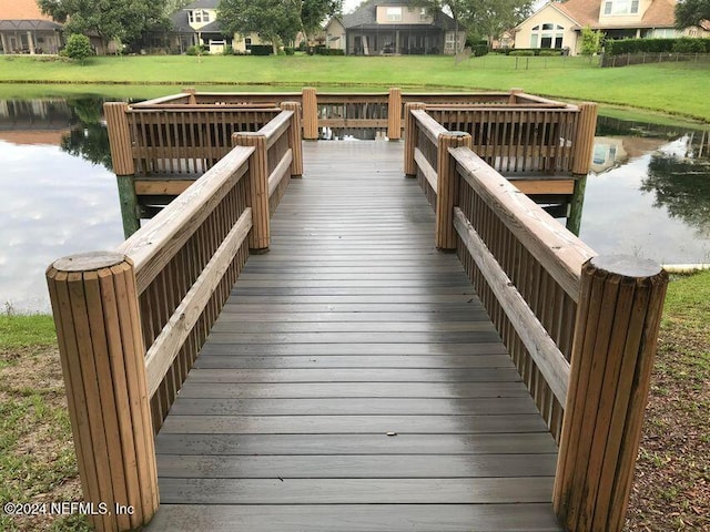 view of dock with a water view and a lawn