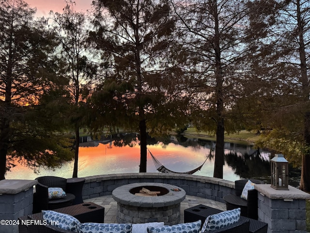 patio terrace at dusk with a water view and an outdoor fire pit