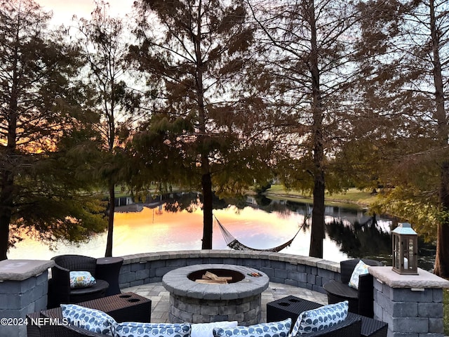 view of property's community featuring a patio area, a water view, and an outdoor fire pit