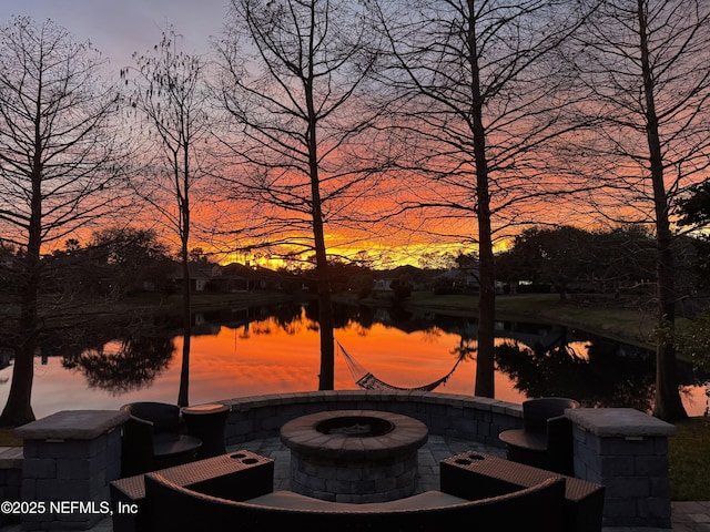 patio terrace at dusk featuring a water view and an outdoor fire pit