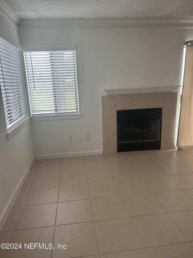 100 Fairway Park Blvd Unit 605, Ponte Vedra Beach, FL 32082 - unfurnished living room featuring a textured ceiling, ornamental molding, a tiled fireplace, light tile patterned floors, and baseboards