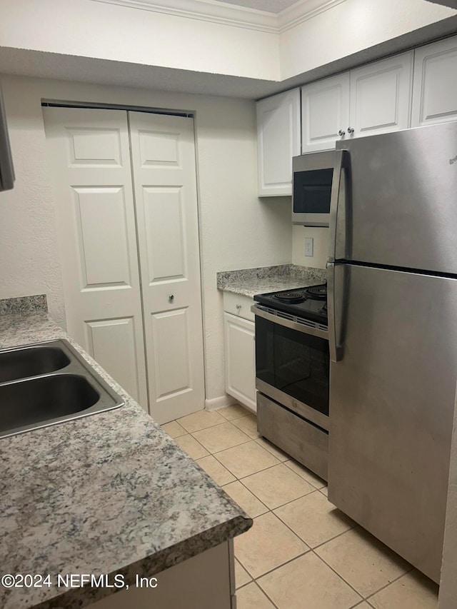 kitchen with light tile patterned flooring, sink, white cabinets, stainless steel appliances, and crown molding