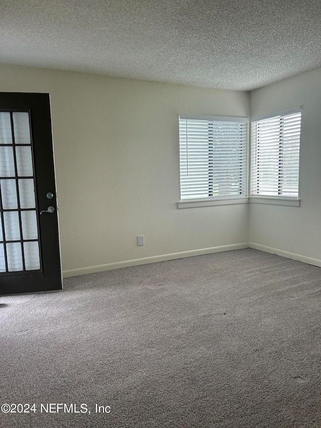 empty room with a textured ceiling and carpet floors