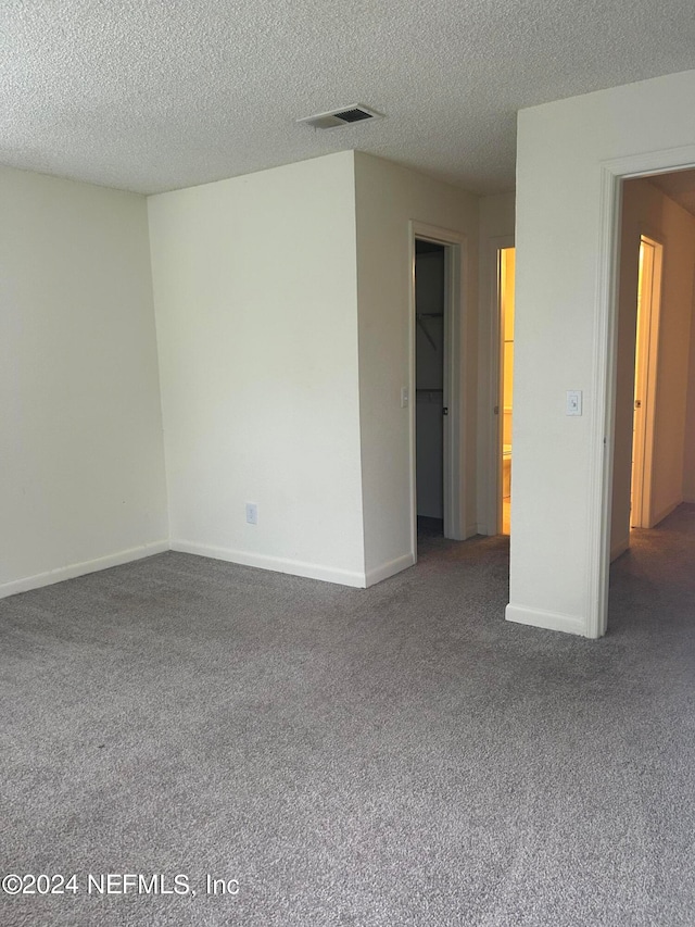 unfurnished room featuring a textured ceiling and carpet flooring