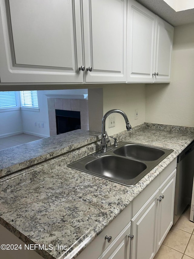 kitchen featuring white cabinets, stainless steel dishwasher, light tile patterned floors, and sink