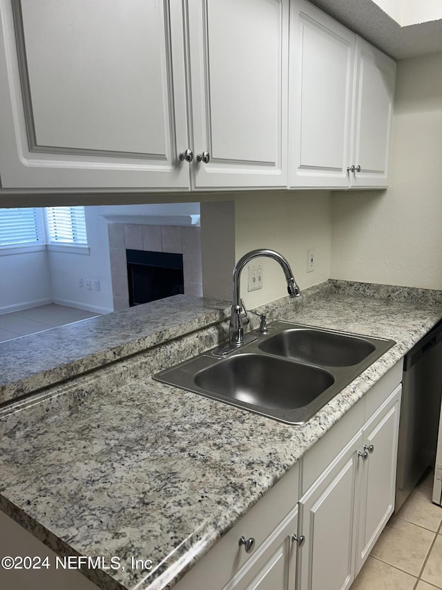 100 Fairway Park Blvd Unit 605, Ponte Vedra Beach, FL 32082 - kitchen featuring a sink, dishwasher, white cabinets, a tiled fireplace, and light tile patterned floors