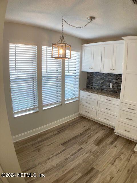 kitchen with pendant lighting, backsplash, dark wood-type flooring, and white cabinets