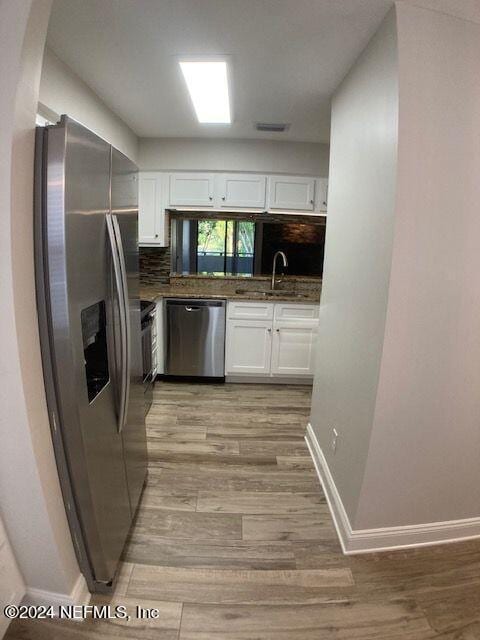 kitchen featuring sink, white cabinets, decorative backsplash, stainless steel appliances, and light hardwood / wood-style flooring