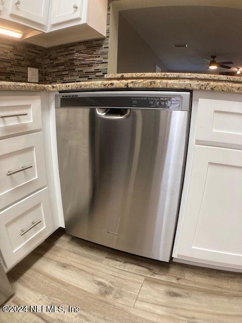 interior details with light hardwood / wood-style floors, white cabinets, stone countertops, decorative backsplash, and stainless steel dishwasher