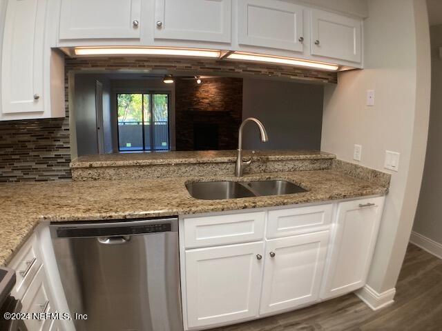 kitchen with sink, white cabinetry, tasteful backsplash, light stone counters, and dishwasher