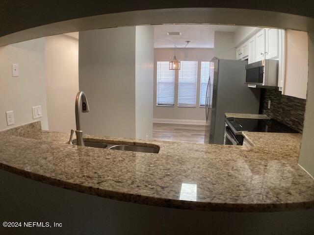 kitchen with pendant lighting, tasteful backsplash, white cabinetry, sink, and stainless steel appliances