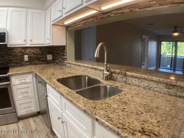 kitchen featuring light stone counters, sink, tasteful backsplash, and white cabinets