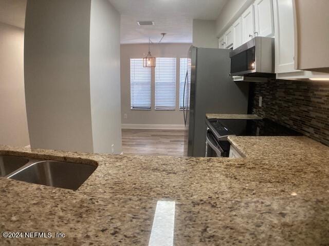 kitchen with decorative light fixtures, tasteful backsplash, white cabinets, electric range, and light stone countertops