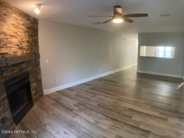 unfurnished living room featuring ceiling fan, dark hardwood / wood-style floors, and a fireplace