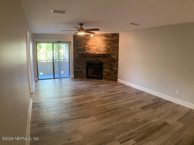 unfurnished living room with a fireplace, dark hardwood / wood-style floors, and ceiling fan