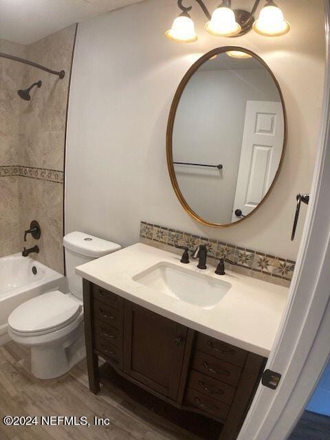 full bathroom with wood-type flooring, toilet, tiled shower / bath combo, and vanity