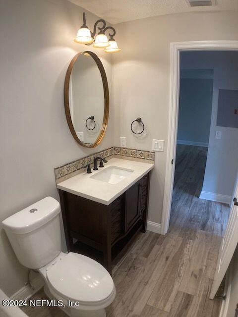 bathroom with hardwood / wood-style flooring, vanity, toilet, and a textured ceiling