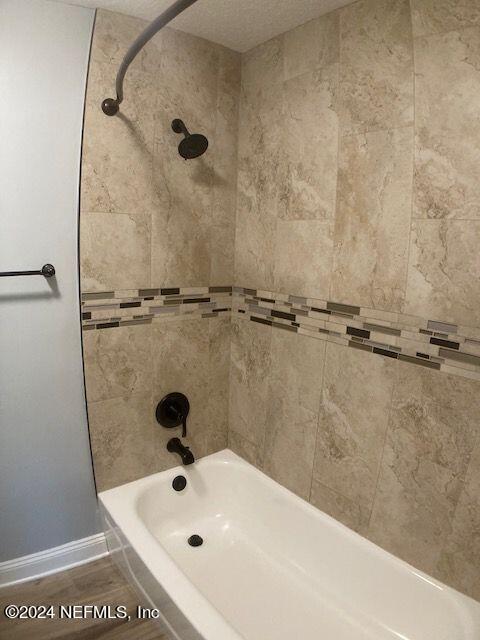 bathroom featuring wood-type flooring and tiled shower / bath