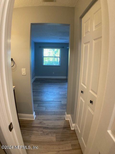 hallway with dark wood-type flooring and a textured ceiling