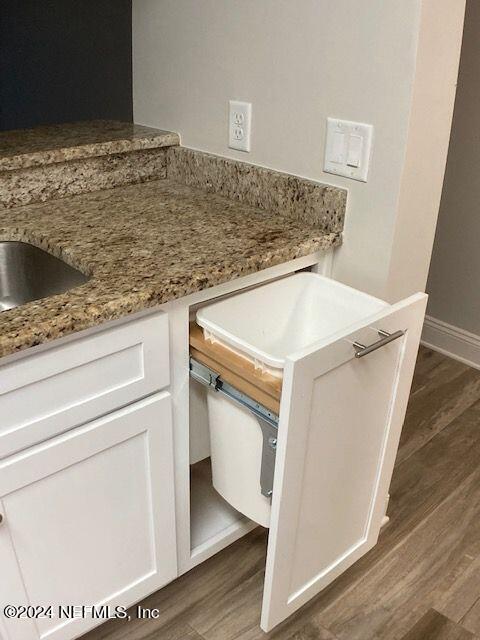 kitchen with white cabinetry, light stone countertops, and dark hardwood / wood-style floors