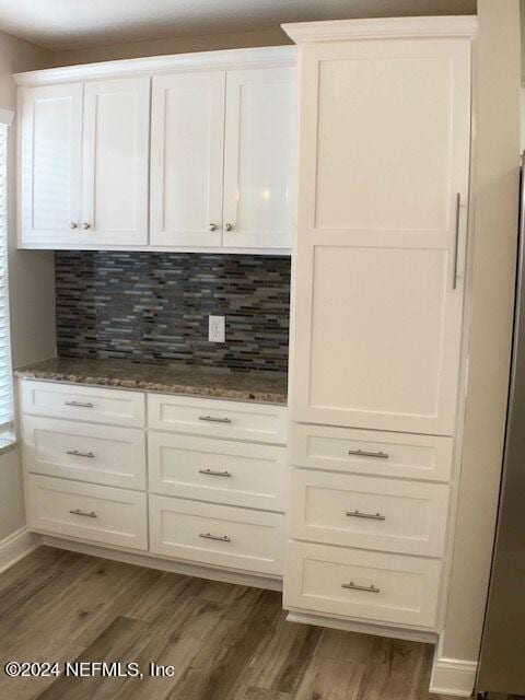 kitchen with white cabinetry, tasteful backsplash, dark hardwood / wood-style floors, and dark stone countertops