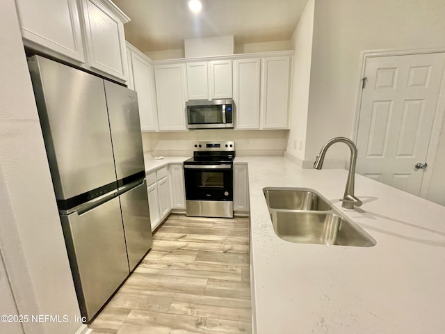 kitchen with light hardwood / wood-style floors, sink, white cabinetry, and stainless steel appliances