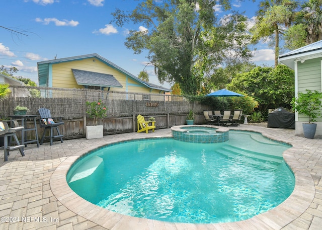 view of swimming pool featuring a patio area, an outdoor bar, a grill, and an in ground hot tub