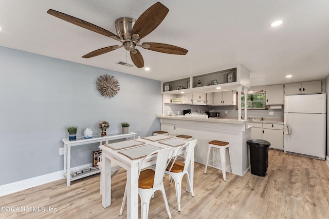 dining space featuring a textured ceiling, light hardwood / wood-style flooring, and ceiling fan