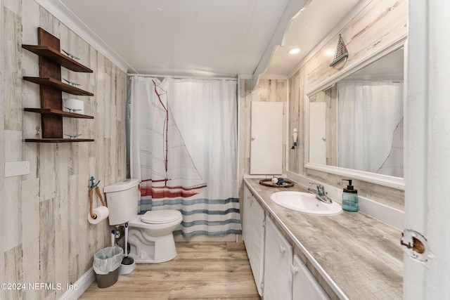 bathroom with wood walls, toilet, vanity, hardwood / wood-style flooring, and ornamental molding