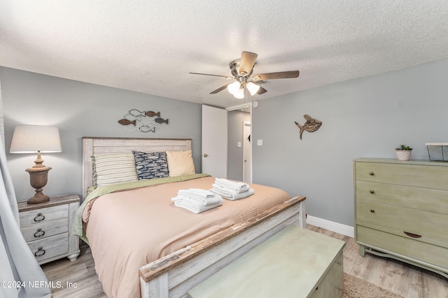 bedroom with light hardwood / wood-style floors, a textured ceiling, and ceiling fan