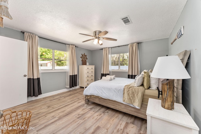 bedroom with multiple windows, ceiling fan, and light wood-type flooring