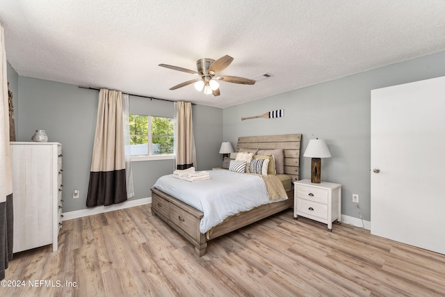 bedroom with a textured ceiling, ceiling fan, and light wood-type flooring