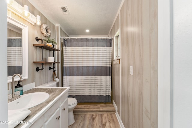 bathroom featuring vanity, a textured ceiling, hardwood / wood-style flooring, and toilet